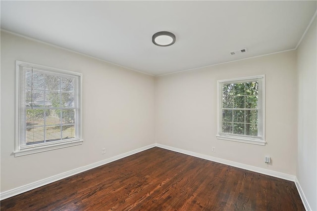 empty room featuring dark wood-type flooring and ornamental molding