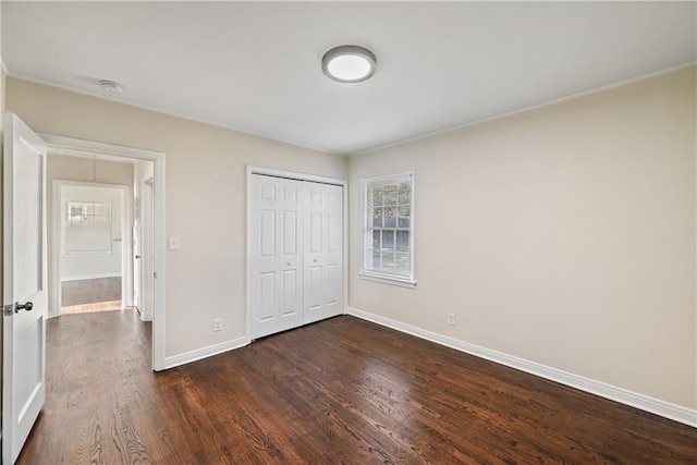 unfurnished bedroom with dark wood-type flooring and a closet