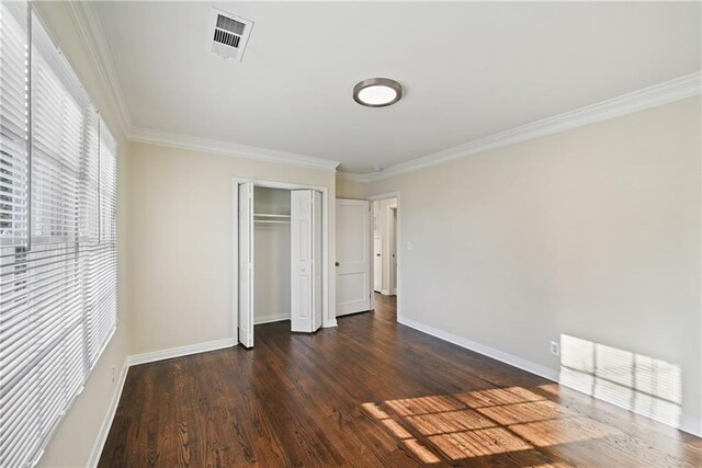 unfurnished bedroom with crown molding, dark wood-type flooring, and a closet