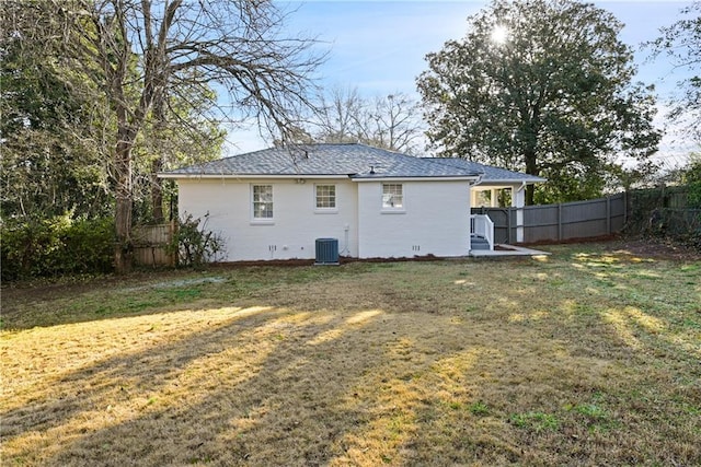 back of property featuring central AC and a lawn