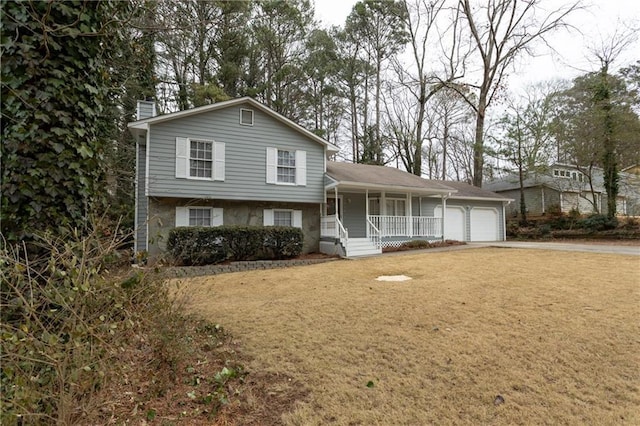 split level home with covered porch, a front yard, and a garage