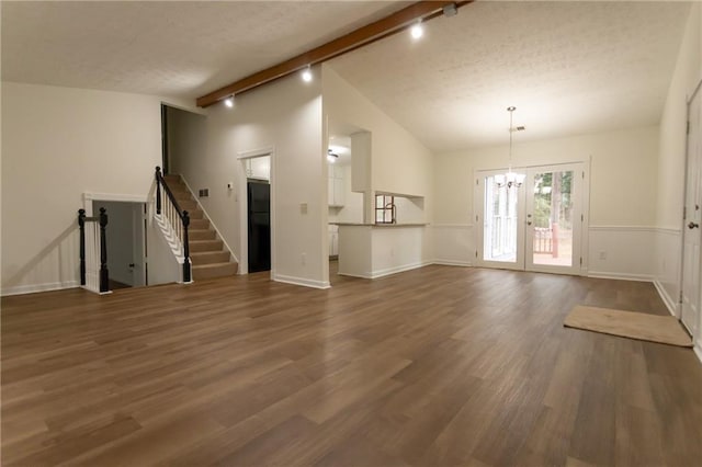 unfurnished living room with a textured ceiling, track lighting, dark hardwood / wood-style flooring, vaulted ceiling with beams, and a notable chandelier