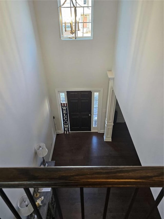 entryway with a healthy amount of sunlight, a towering ceiling, baseboards, and dark wood finished floors