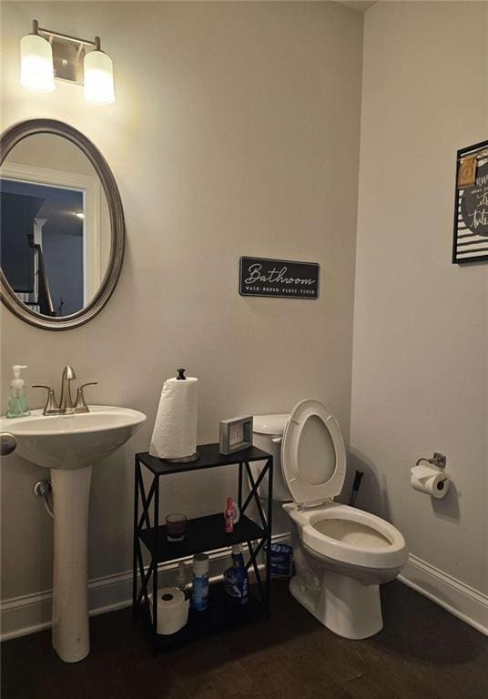 half bathroom featuring toilet and baseboards