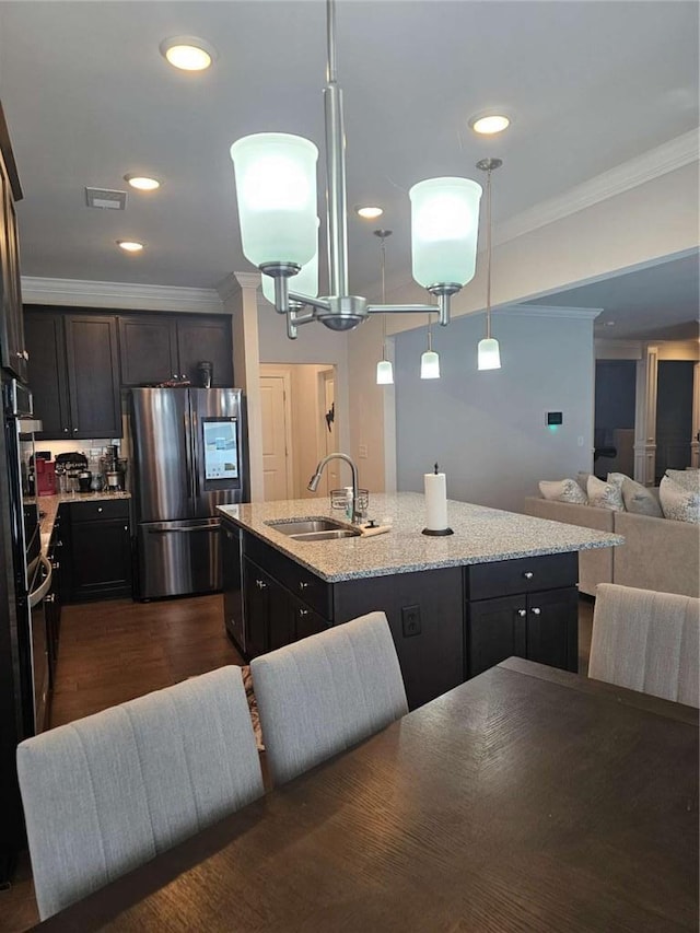 kitchen featuring an island with sink, open floor plan, crown molding, smart refrigerator, and a sink