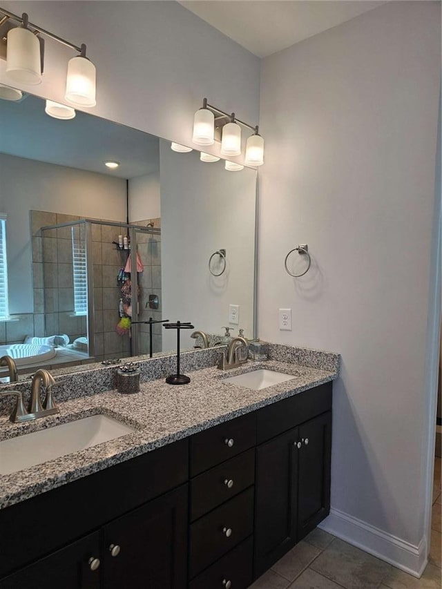 bathroom with double vanity, a stall shower, tile patterned flooring, and a sink