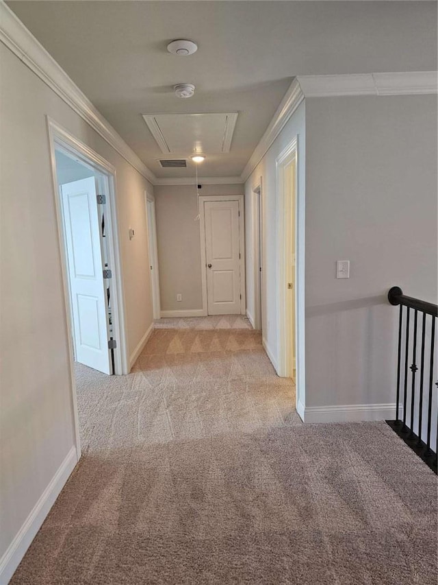 hallway featuring ornamental molding, carpet flooring, attic access, and baseboards