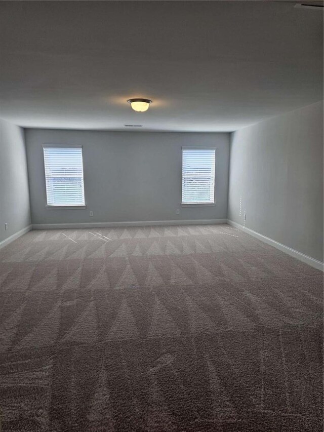 spare room featuring plenty of natural light, baseboards, and light colored carpet