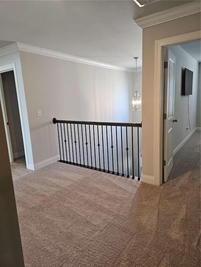 carpeted empty room with baseboards, ornamental molding, and a notable chandelier