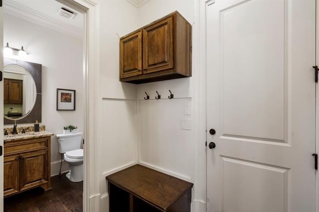 mudroom featuring dark wood-style floors, crown molding, visible vents, and a sink