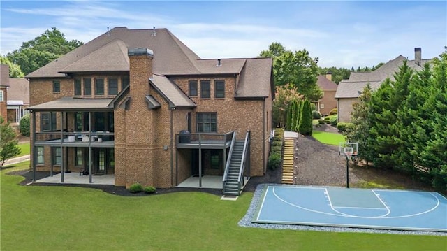 back of house featuring a yard, a chimney, basketball hoop, stairway, and a patio area