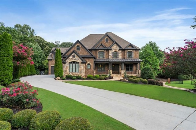 view of front facade with a standing seam roof, metal roof, stone siding, driveway, and a front lawn