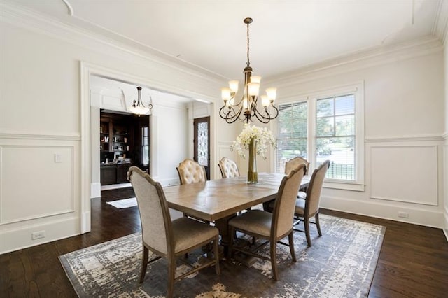 dining area featuring dark wood-style floors, ornamental molding, an inviting chandelier, and a decorative wall