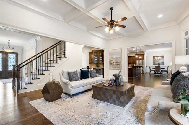 living area with beam ceiling, coffered ceiling, dark wood finished floors, and stairway