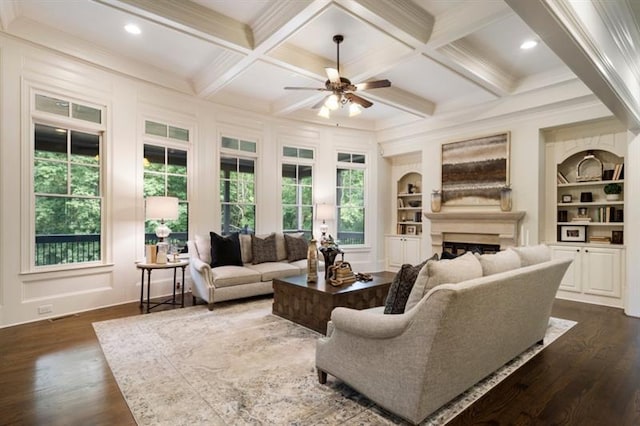 living room with built in shelves, beam ceiling, and a healthy amount of sunlight