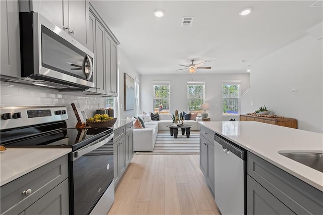 kitchen with appliances with stainless steel finishes, gray cabinets, and open floor plan