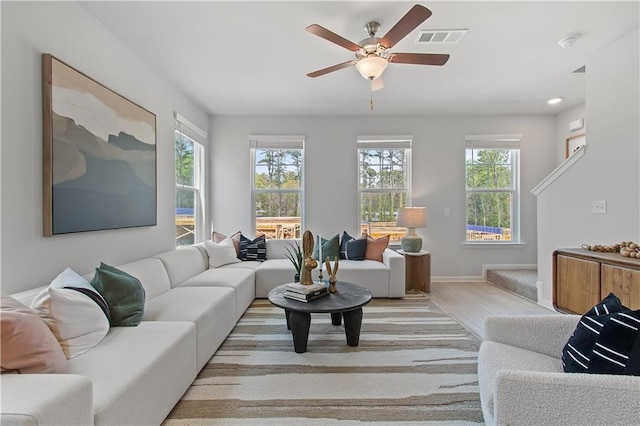 living area featuring a ceiling fan, light wood-type flooring, visible vents, and baseboards