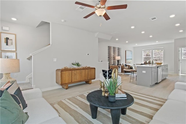 living room featuring light wood-type flooring, recessed lighting, visible vents, and stairway