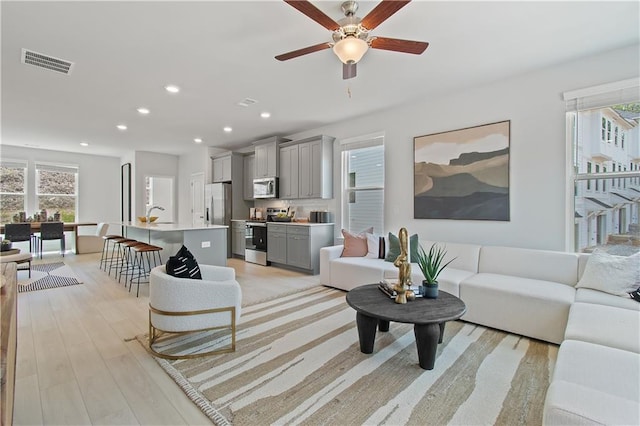 living area with a ceiling fan, light wood-type flooring, visible vents, and recessed lighting