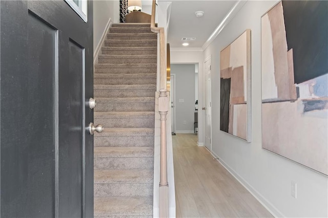 stairs with baseboards, visible vents, ornamental molding, and wood finished floors