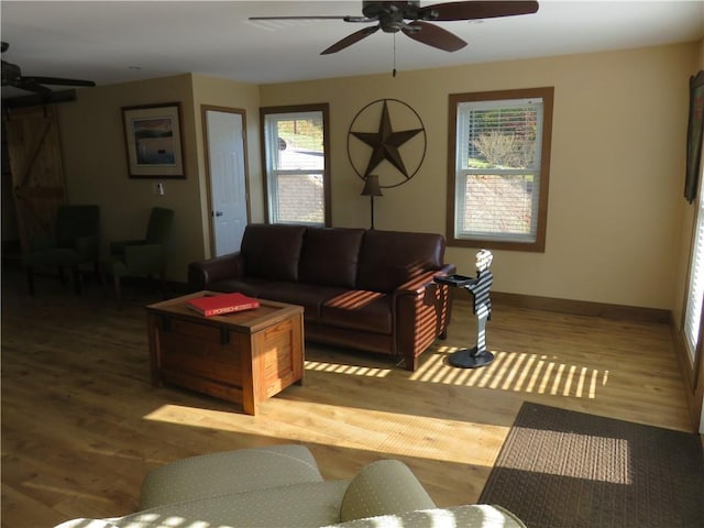 living area with a healthy amount of sunlight, baseboards, a ceiling fan, and wood finished floors