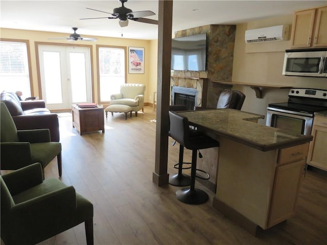 kitchen featuring open floor plan, appliances with stainless steel finishes, a wall mounted air conditioner, and a kitchen breakfast bar