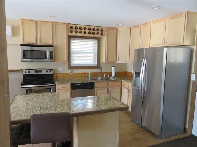 kitchen with light wood-type flooring, a sink, light brown cabinets, and stainless steel appliances