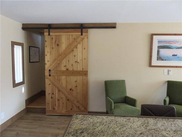 living area featuring a barn door, baseboards, and wood finished floors