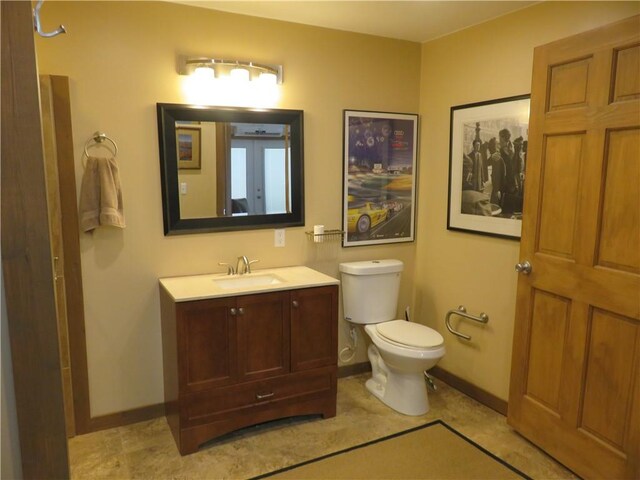 bathroom featuring baseboards, toilet, and vanity