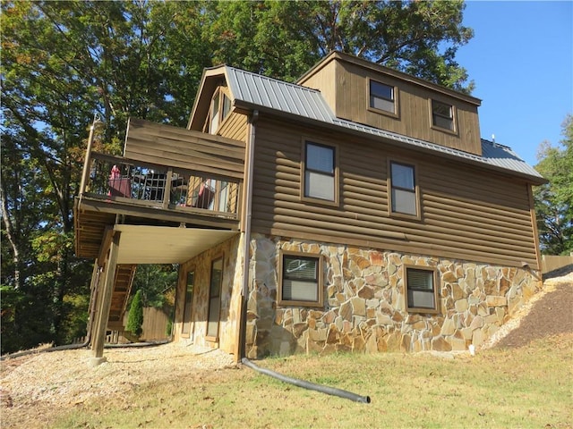 rear view of house featuring a lawn, log veneer siding, stone siding, and metal roof