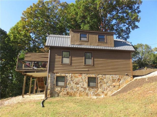 view of side of home featuring a yard, a wooden deck, stone siding, and faux log siding