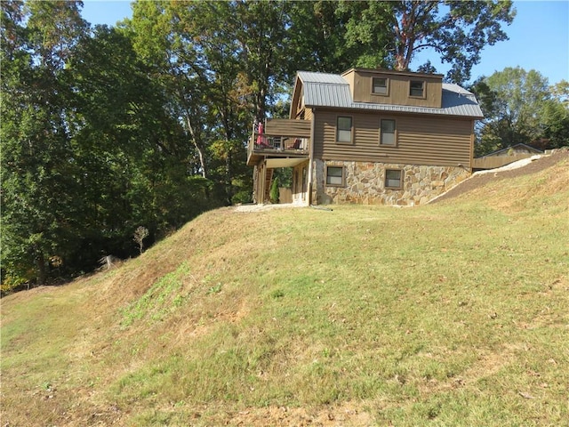 rear view of house with a lawn, metal roof, and stone siding
