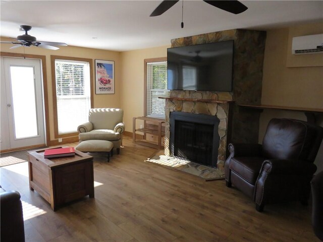 living room with ceiling fan, a wall unit AC, wood finished floors, and a fireplace