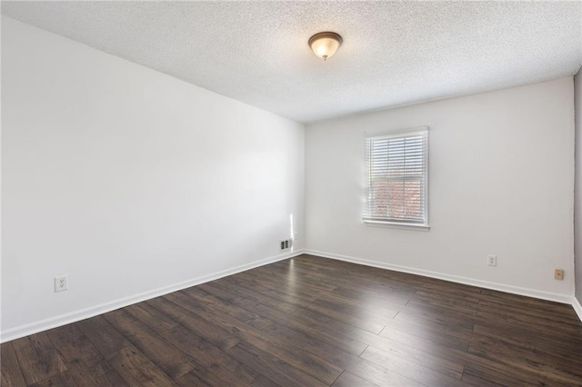 empty room featuring a textured ceiling and dark hardwood / wood-style flooring