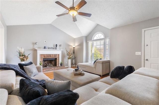 living room with a textured ceiling, ceiling fan, vaulted ceiling, and a brick fireplace