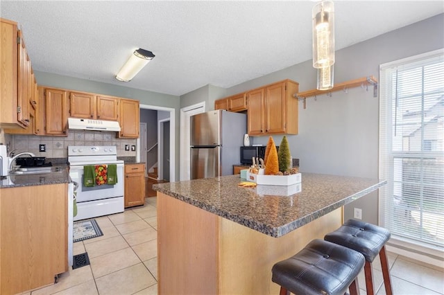 kitchen featuring pendant lighting, sink, stainless steel fridge, decorative backsplash, and electric range