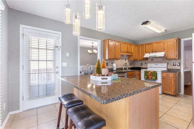 kitchen featuring hanging light fixtures, white electric range oven, decorative backsplash, and light tile patterned floors