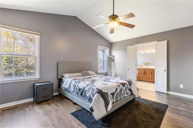 bedroom with hardwood / wood-style flooring, vaulted ceiling, ensuite bath, and ceiling fan