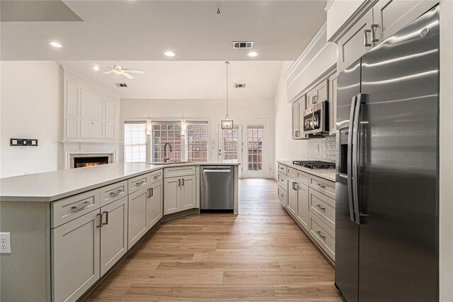 401 Wellwood Way, Roswell, GA 30075 - kitchen with appliances with stainless steel finishes, a ceiling fan, light countertops, light wood-style flooring, and a large fireplace