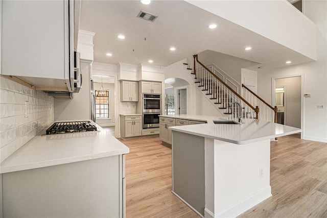 401 Wellwood Way, Roswell, GA 30075 - kitchen featuring appliances with stainless steel finishes, arched walkways, recessed lighting, decorative backsplash, and light wood finished floors