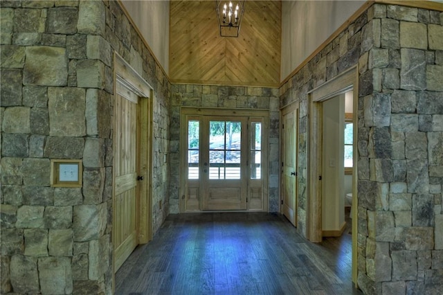 entrance foyer featuring an inviting chandelier, a towering ceiling, and dark hardwood / wood-style floors