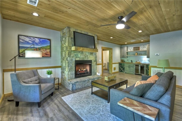 living room with wood ceiling, a stone fireplace, and hardwood / wood-style flooring