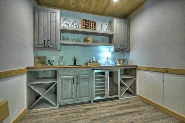 bar with wood-type flooring, sink, beverage cooler, and wood ceiling