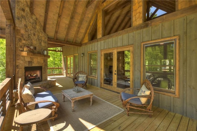 sunroom with wood ceiling, a stone fireplace, and lofted ceiling with beams