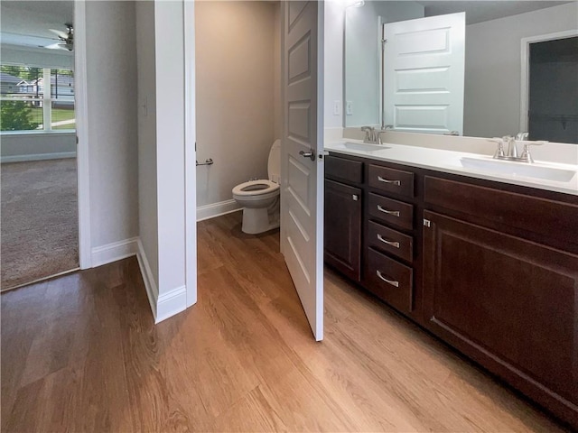 bathroom with hardwood / wood-style floors, vanity, toilet, and ceiling fan