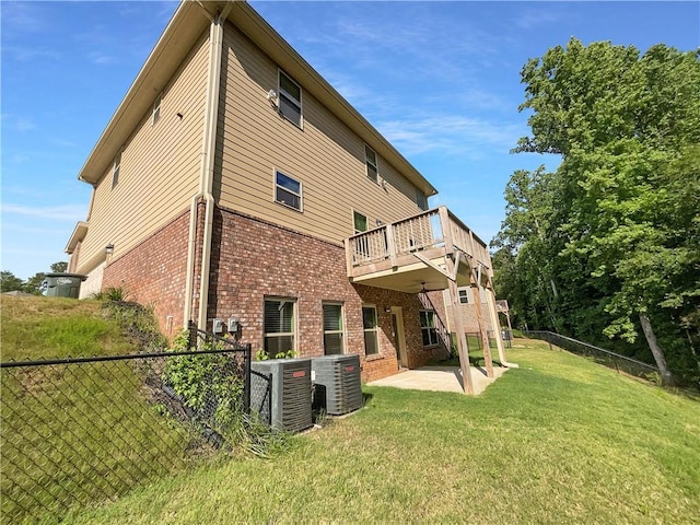 rear view of property featuring a lawn, central AC, a patio area, and a wooden deck