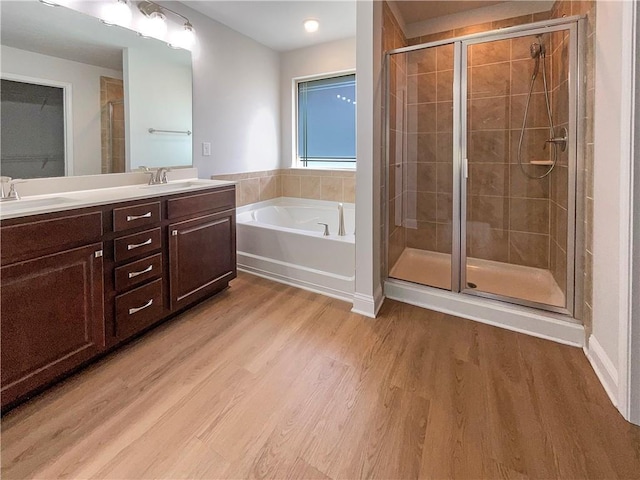 bathroom featuring hardwood / wood-style flooring, vanity, and plus walk in shower