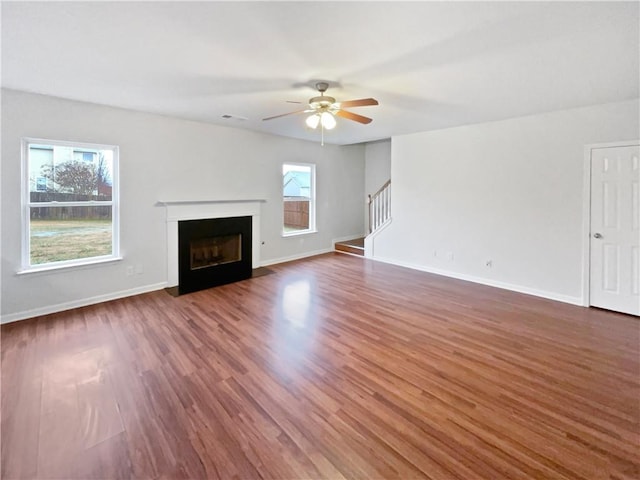 unfurnished living room with stairway, a fireplace with flush hearth, baseboards, and dark wood-style flooring