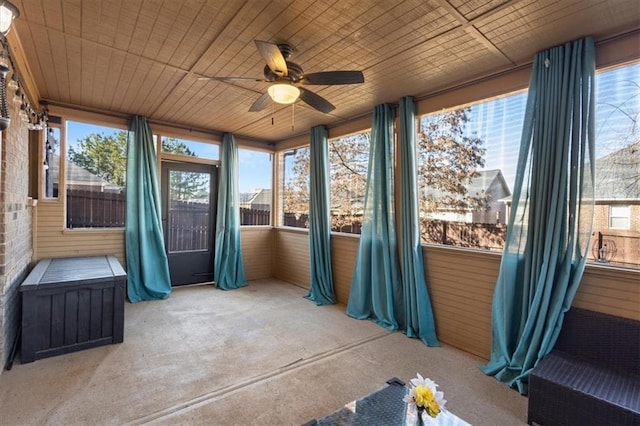 unfurnished sunroom featuring ceiling fan, wooden ceiling, and a wealth of natural light