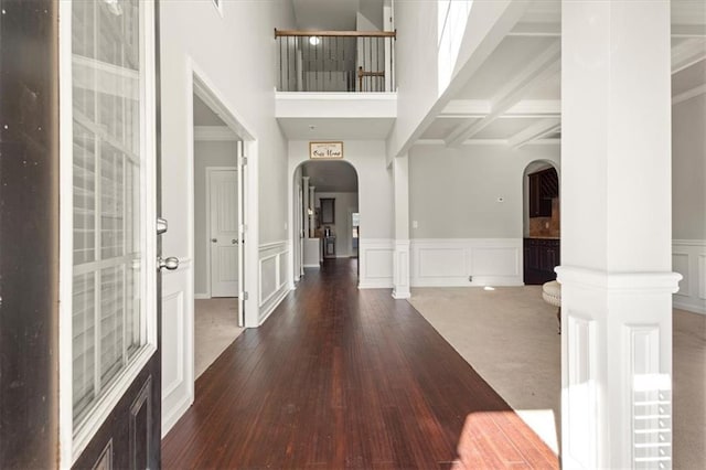 foyer featuring dark wood-type flooring, beam ceiling, and a high ceiling